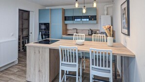A modern kitchen with a central island, white chairs, and blue cabinets. - 1 bedroom beautiful apartment in Gagny (Gagny)
