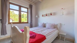 A bedroom with a wooden bed, a red blanket, and a window with curtains. - 2 bedroom beautiful home in Krzeszna (Krzeszna)
