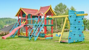 A playground with a slide, climbing wall, and swings. - 2 bedroom beautiful home in Krzeszna (Krzeszna)