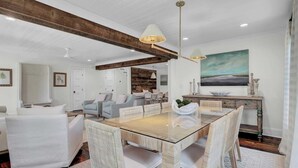 A spacious living room with a wooden ceiling, a glass-top dining table surrounded by wicker chairs, and a rustic wooden bench. - Be a Sullivans Local! 1307 Cove Avenue by Avantstay Pool + Outdoor Living (Sullivan's Island)