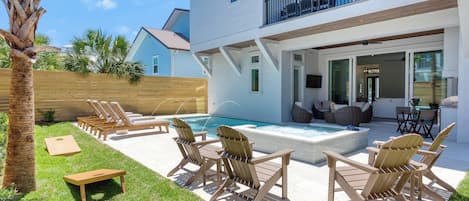 Una casa de dos pisos con piscina, mobiliario exterior y terraza de madera.