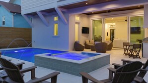 Een buitenzwembad met ligbedden en een jacuzzi.