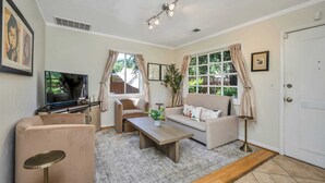 A living room with a sofa, armchair, coffee table, TV, and a small table with a plant. - Grapevine Cottage by Avantstay Private Vineyard + Outdoor/indoor Living + Firepit + Minutes to Glen Ellen (Glen Ellen)