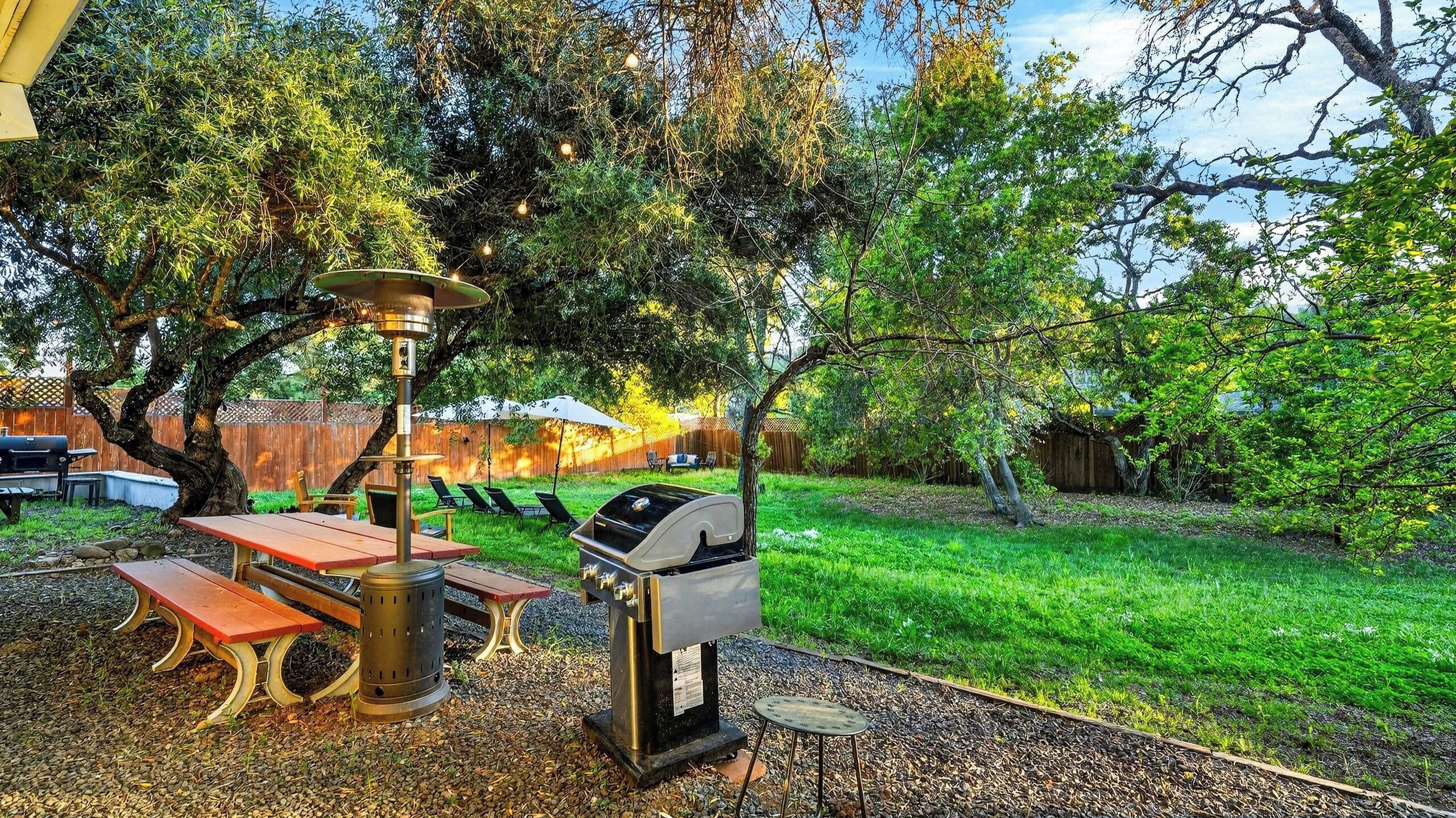 A backyard with a grill, picnic table, and outdoor seating area.