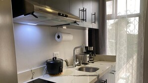 Una cocina moderna con estufa integrada, cafetera y una olla sobre la encimera.