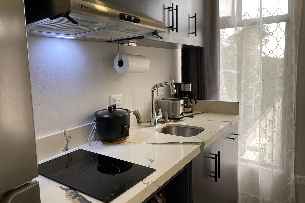 A modern kitchen with a built-in stove, a coffee maker, and a pot on the counter.