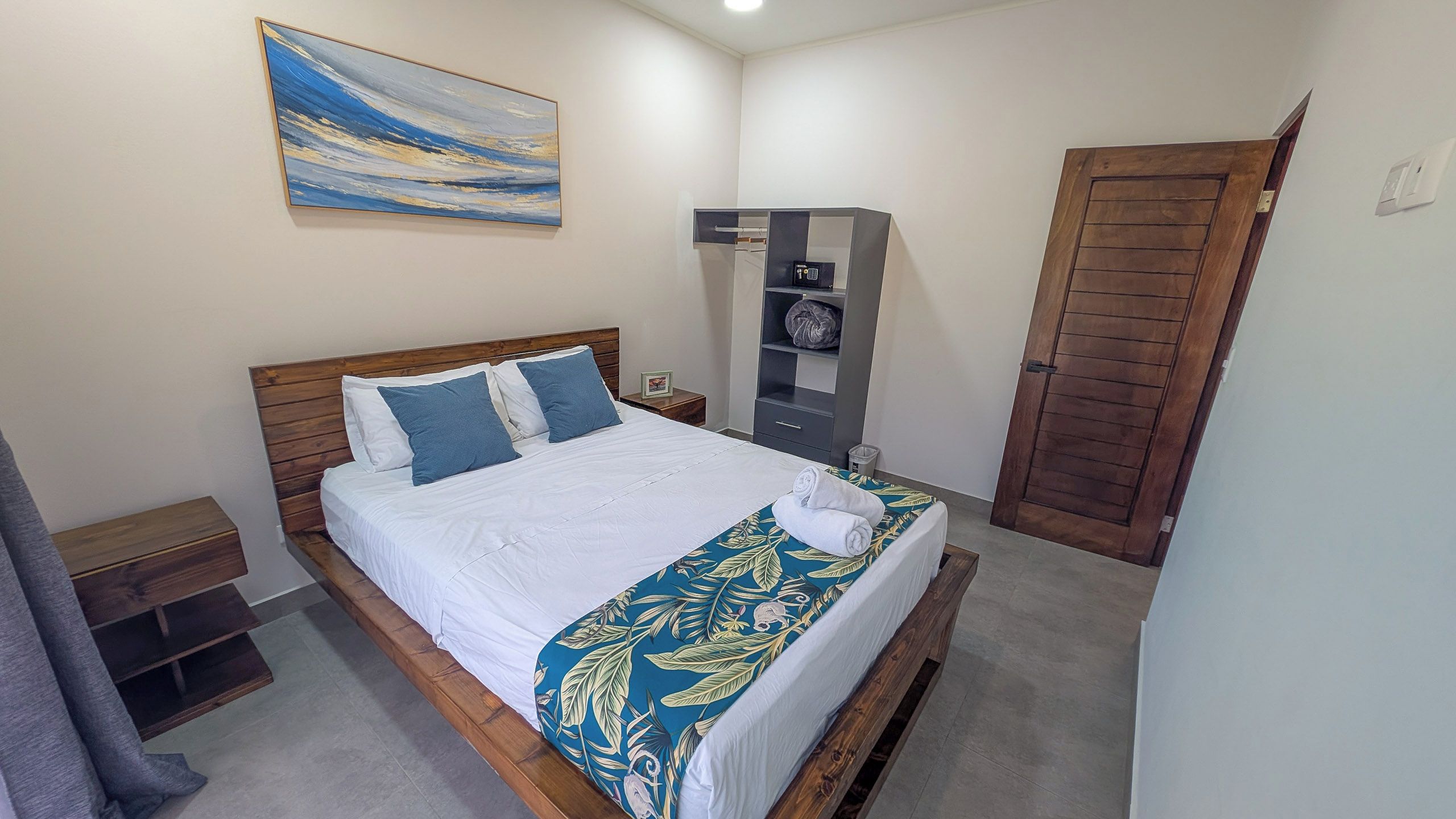 A neatly made bed with a white and blue bedspread, a wooden headboard, and a single pillow.