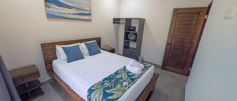 A neatly made bed with a white and blue bedspread, a wooden headboard, and a single pillow.