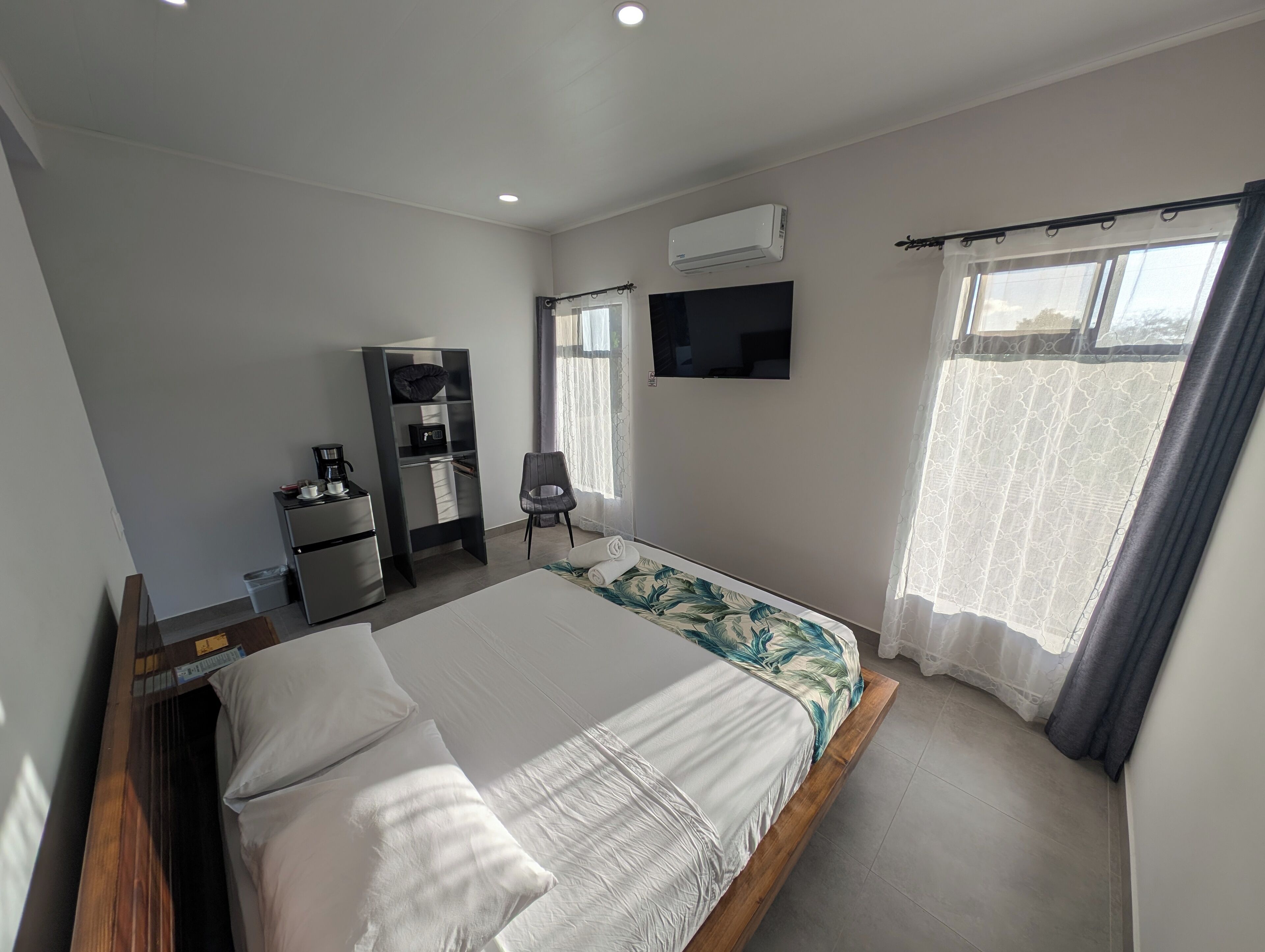 A modern hotel room with a bed, a desk, a chair, a wardrobe, and a TV.