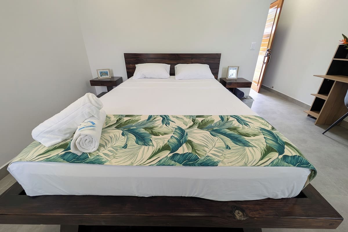 A neatly made bed with a floral bedspread, two bedside tables with lamps, and a wooden nightstand.