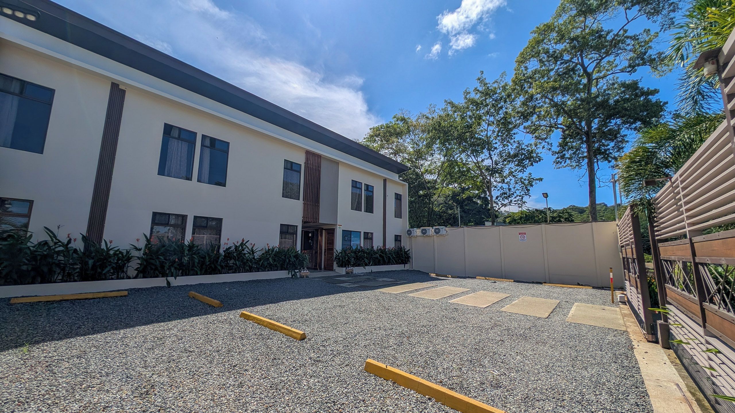 A building with a flat roof, multiple windows, and a gravel parking area.