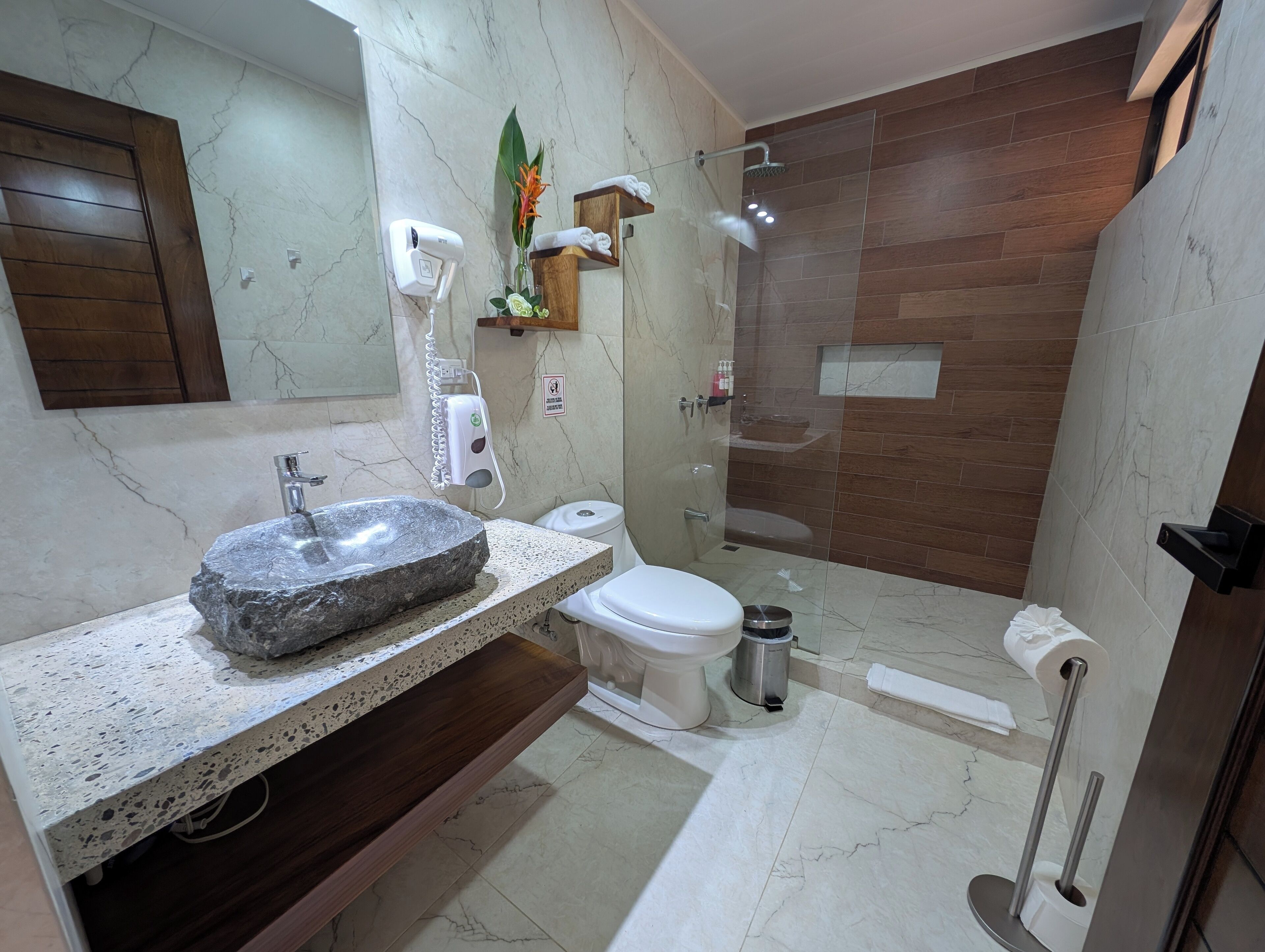 Een moderne badkamer met een wasbak van steen, toilet en douchecabine met glazen wanden.