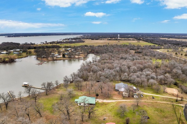 Stunning aerial view of lakefront home with private dock and scenic surroundings