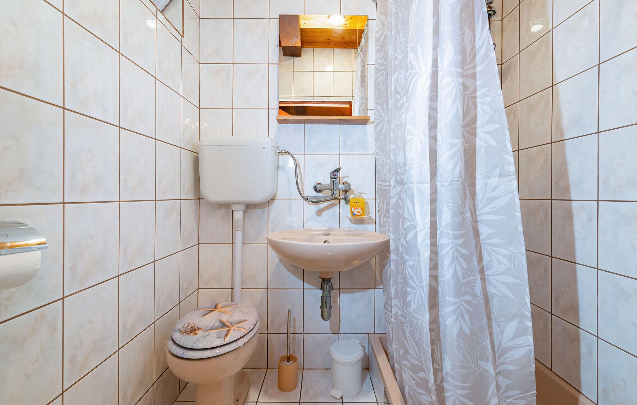 A bathroom with a toilet, sink, and shower curtain.