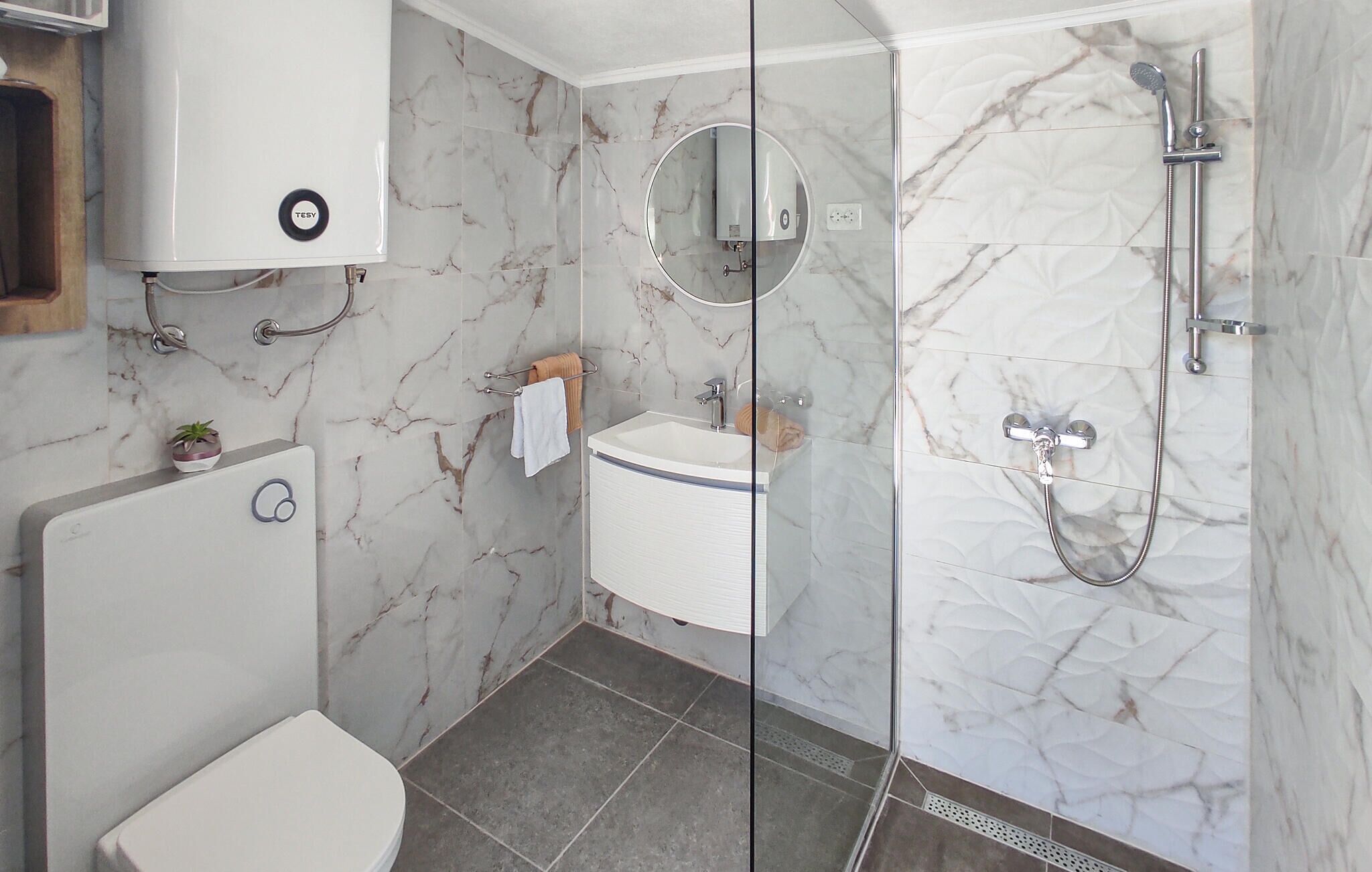 Une salle de bain moderne équipée de toilettes, d’un lavabo et d’une douche.