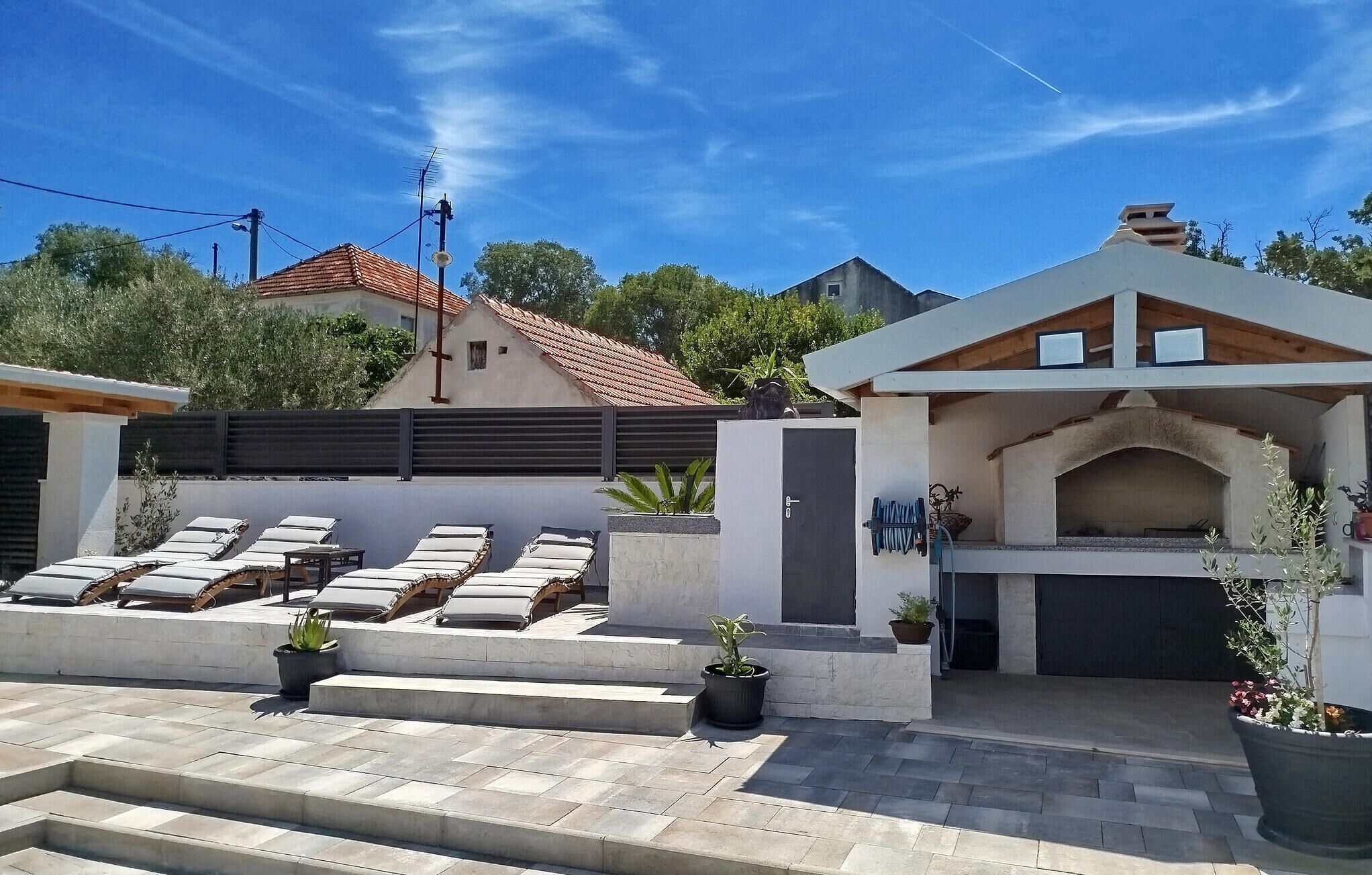 Uma casa moderna com um espaço de pátio que inclui espreguiçadeiras e churrasqueira.