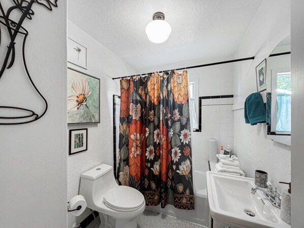 A bathroom with a toilet, sink, and shower curtain.