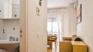 En smal hall leder till ett matområde med ett träbord och stolar, ett handfat och ett litet skåp.