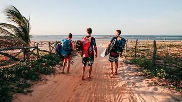 Leading to a serene beach, this natural pathway is lined with palm trees and a wooden fence.