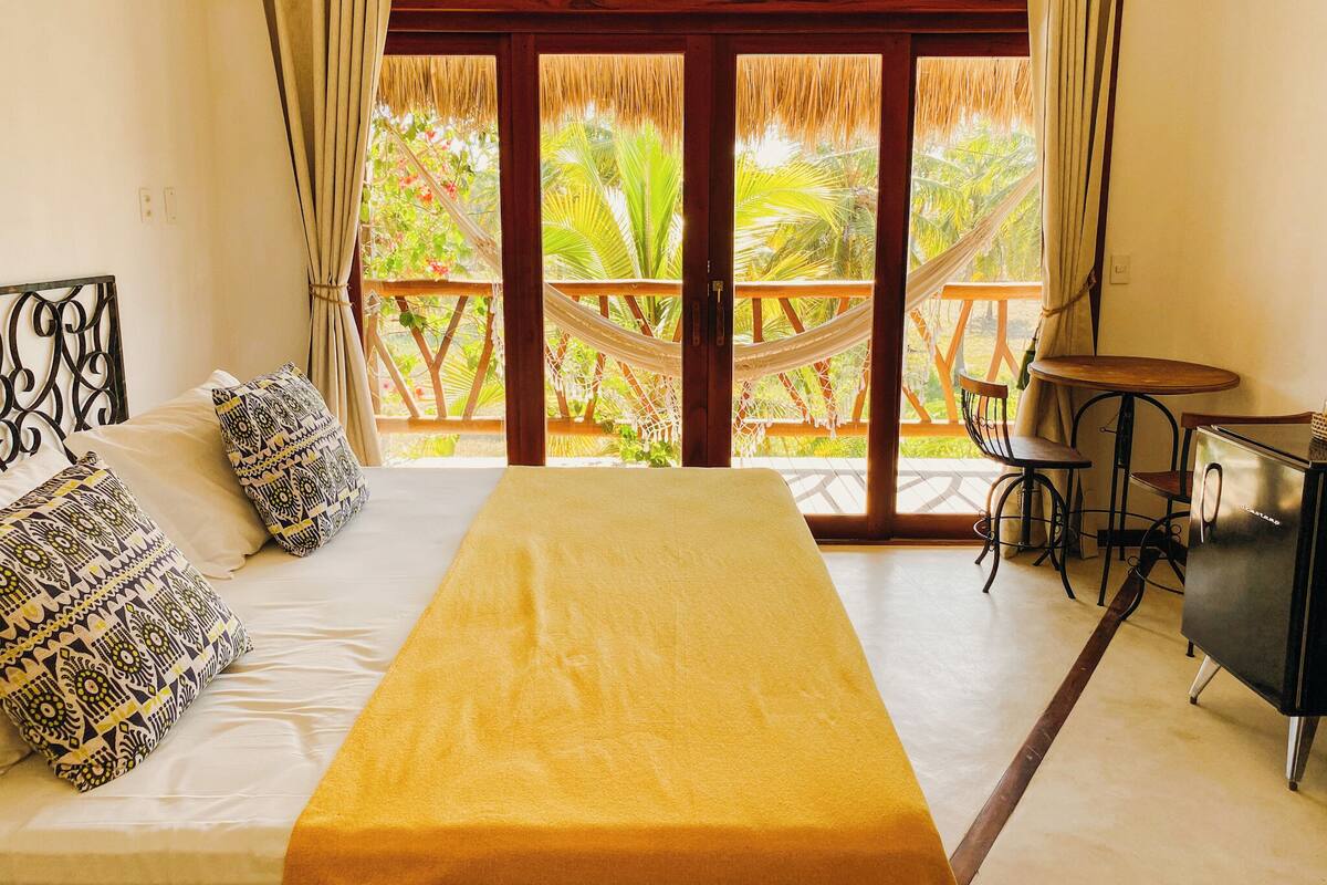 A room with a bed, a small table, and a hammock.