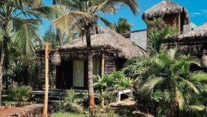 A tropical resort with thatched-roof huts, palm trees, and a wooden deck. - Pousada Vayú  (Amontada)
