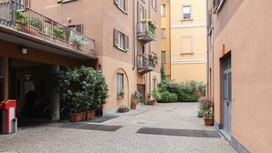 A courtyard with cobblestone pavement, potted plants, and a bike rack.
