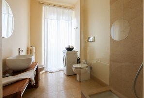 A bathroom with a large sink, toilet, and a washing machine.