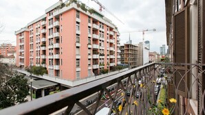 A multi-story building with balconies, a pedestrian bridge, and a busy street below.