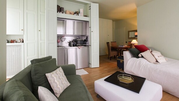 A compact living space with a kitchenette, a dining area, and a bedroom.