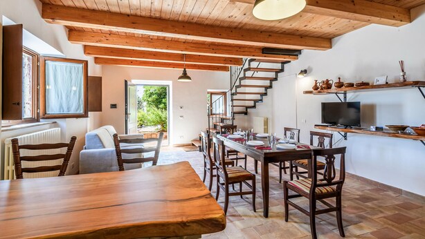 Un vaste espace dédié à la salle à manger, avec des meubles en bois, un escalier et un téléviseur posé sur une étagère.