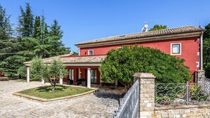 Un bâtiment rouge avec un toit en tuiles, des murs en pierre et une cour dallée.