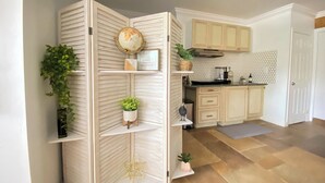 A kitchen with wooden cabinets, a coffee maker, and a decorative globe on a shelf. - Private Paradise - Large, Peaceful Studio w Patio (Naples)