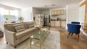 A modern living room with a glass coffee table, a beige sofa, and a blue armchair. - Private Paradise - Large, Peaceful Studio w Patio (Naples)