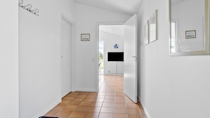 A hallway with white walls, a tiled floor, and a door leading to a room with a television and a window. - Lovely home in Hurup Thy with WiFi (Hurup Thy)