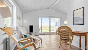A spacious room with a large sliding glass door leading to an outdoor area, wicker furniture, and a framed map on the wall. - Lovely home in Hurup Thy with WiFi (Hurup Thy)