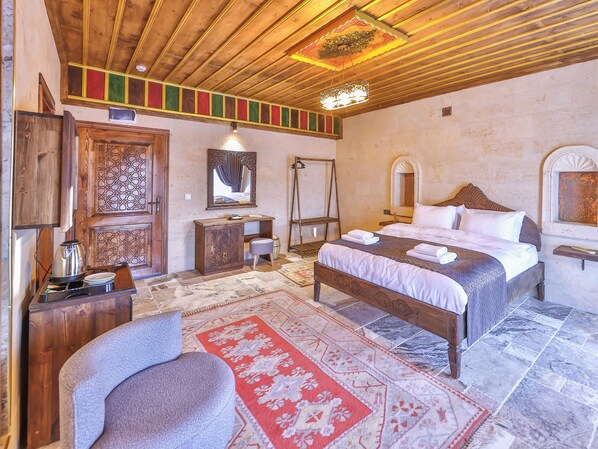 Un dormitorio con techo de madera, una cama con ropa de cama blanca, un aparador de madera, un espejo y una alfombra roja con estampado.