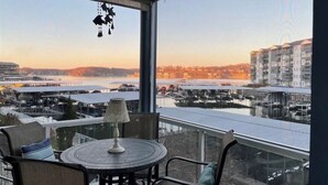 A balcony with a round table and chairs, overlooking a marina with boats and buildings across the water. - Lakeside Condo! Pool/HotTub! 3 MasterSuites! MC1C (Lake Ozark)
