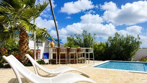 Un espace aménagé au bord de la piscine, avec des chaises longues, une piscine et un bâtiment en arrière-plan.