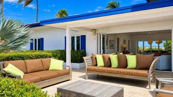 An outdoor seating area with two sofas and a coffee table, surrounded by greenery and palm trees.