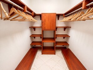 Un armario espacioso con estantes y perchas de madera.
