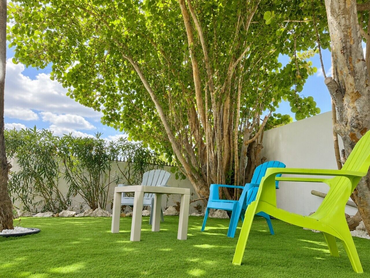 A backyard with a lawn, two chairs, and a table.