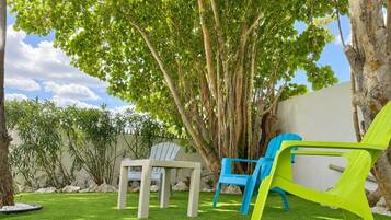 A backyard with a lawn, two chairs, and a table.