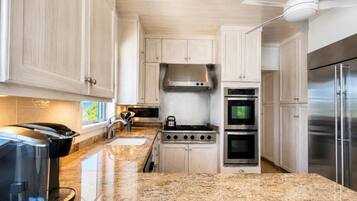 A modern kitchen with granite countertops, stainless steel appliances, and light wood cabinetry.