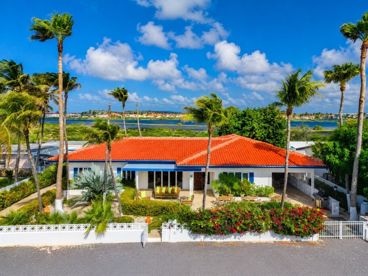 A hotel with a red-tiled roof, a covered outdoor seating area, and a view of the sea.