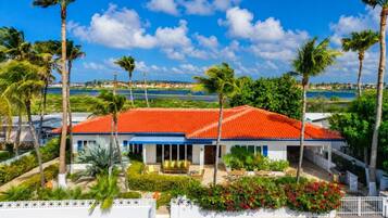 A hotel with a red-tiled roof, a covered outdoor seating area, and a view of the sea.
