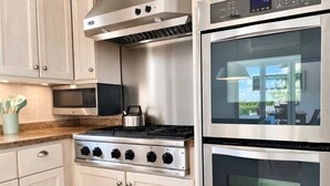 Une cuisine moderne équipée d’appareils électroménagers en acier inoxydable, notamment une cuisinière, un four et un four à micro-ondes.