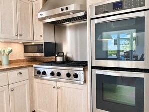 Una cocina moderna con electrodomésticos de acero inoxidable, incluyendo estufa, horno y microondas.