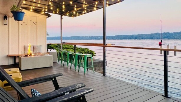Une terrasse dotée d’un foyer, d’un espace salon et offrant une vue sur un plan d’eau.