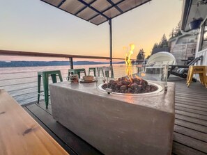 A deck with a fire pit, outdoor seating, and a view of the water. - Modern & Relaxing Waterfront Home on Hood Canal (Belfair)