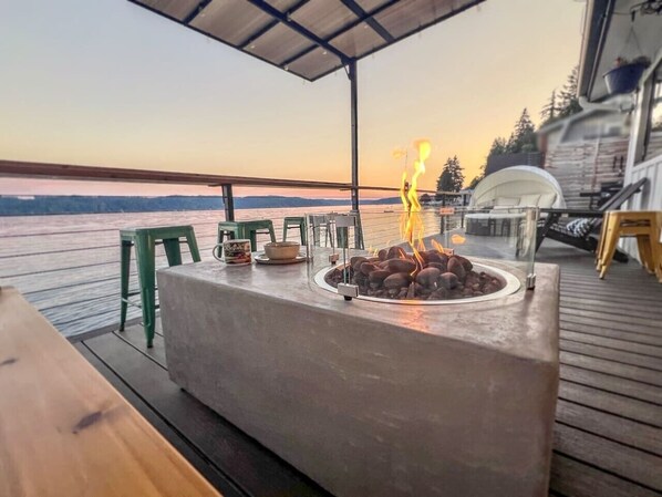 A deck with a fire pit, outdoor seating, and a view of the water.